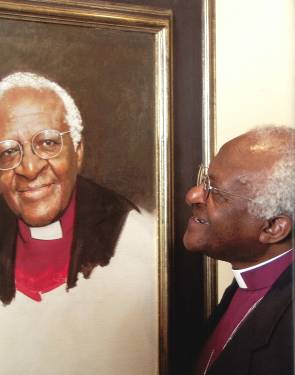 A photograph of Archbishop Desmond Tutu studying his likeness to Richard Stone's painting